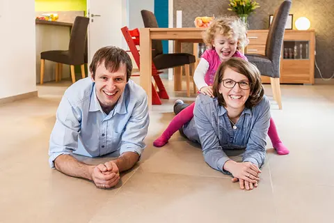 Mamma, pappa och liten dotter ligger p&aring; det uppv&auml;rmda golvet.