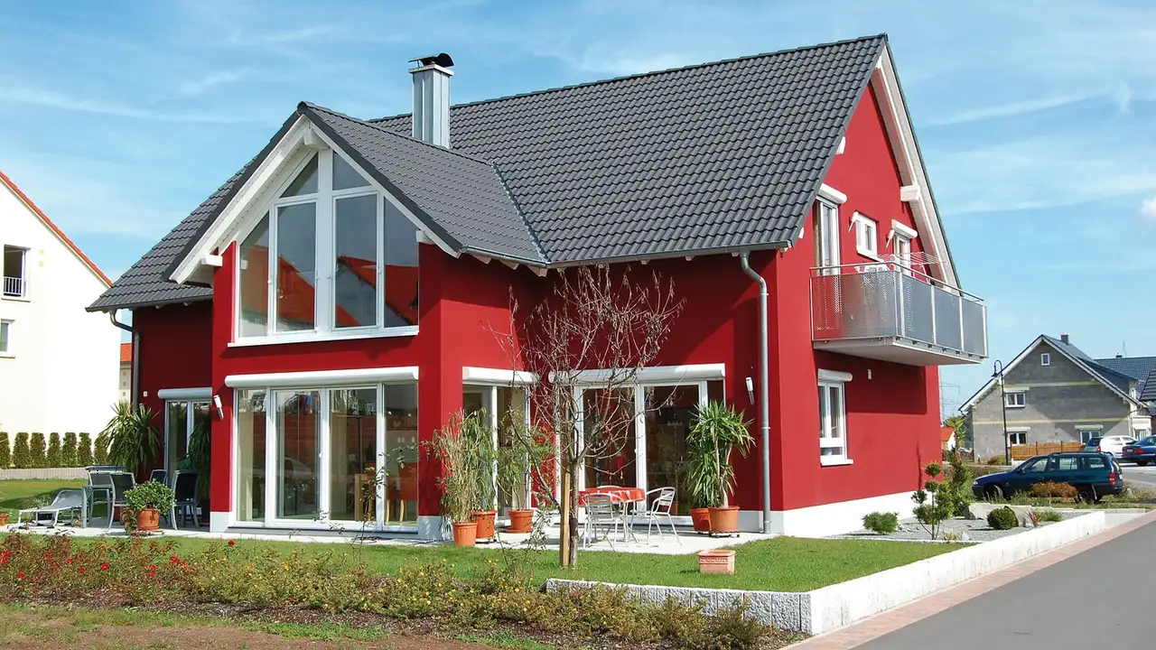 Ett passivhus – med r&ouml;dm&aring;lad fasad och vita f&ouml;nsterfoder – &auml;r optimalt f&ouml;r att komplettera v&auml;rmesystemet med DITRA-HEAT-E.