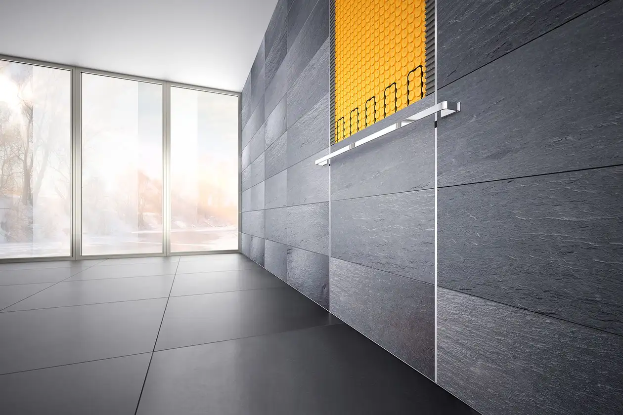 V&auml;gg med gr&aring;a, stora plattor och detaljvy av v&auml;ggv&auml;rmen Schl&uuml;ter-DITRA-HEAT.