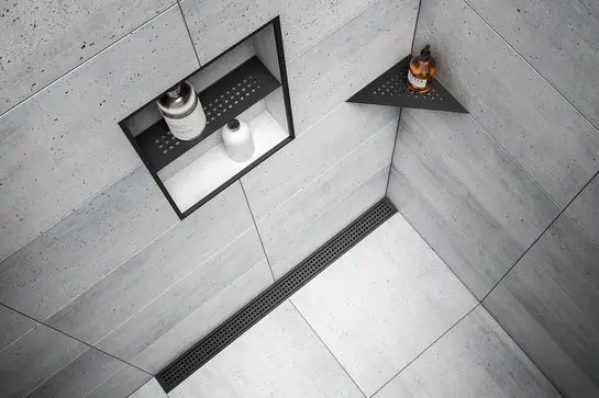 Bild p&aring; duschh&ouml;rna med platts&auml;ttning med betongutseende med mattsvart duschr&auml;nna Schl&uuml;ter-KERDI-LINE och mattsvart duschhylla och nisch i produktserien Schl&uuml;ter-SHELF.