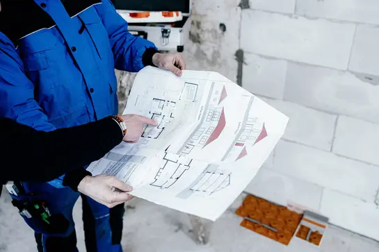 Två konstruktörer tittar på planritningen av en fastighet för att installera golvvärmen BEKOTEC-THERM