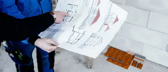 Tv&aring; konstrukt&ouml;rer tittar p&aring; planritningen av en fastighet f&ouml;r att installera golvv&auml;rmen BEKOTEC-THERM