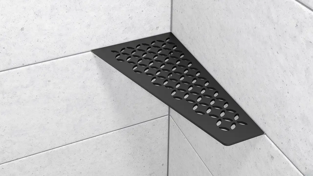 H&auml;r visas en produktn&auml;rbild p&aring; den r&auml;tvinkliga duschh&ouml;rnhyllan Schl&uuml;ter-SHELF-E-S3 i designen FLORAL i f&auml;rgen MGS grafitsvart matt installerad p&aring; ljusgr&aring;tt v&auml;ggkakel