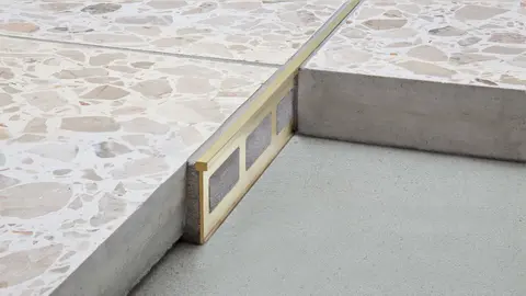 Detaljerad bild p&aring; separations- och dekorprofilen  Schl&uuml;ter-TERRAZZO-M med guldgul profilf&auml;rg.