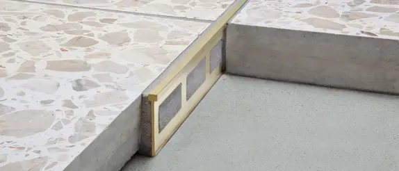Detaljerad bild p&aring; en konstruktion med separationsprofilen Schl&uuml;ter-TERRAZZO-M mellan tv&aring; golvbel&auml;ggningar.