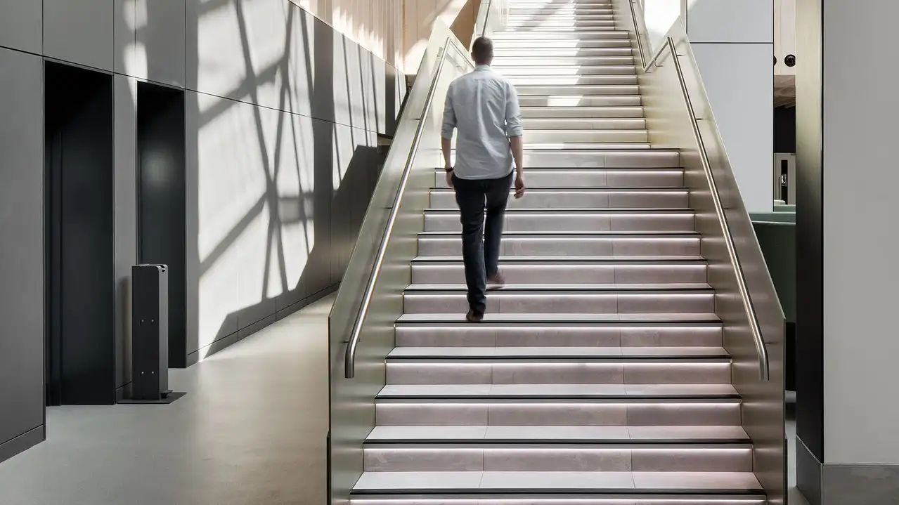 En man g&aring;r uppf&ouml;r en trappa med trappsteg som har indirekt belysning genom Schl&uuml;ter-LIPROTEC