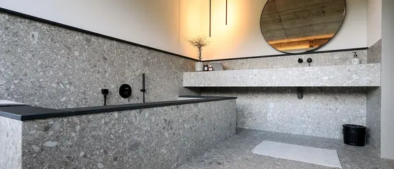 Badrum med stengr&aring;a keramikplattor och produkter som Schl&uuml;ter-KERDI-LINE och Schl&uuml;ter-QUADEC.