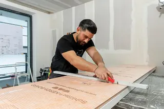 Schl&uuml;ter-Systems-hantverkare sk&auml;r till Schl&uuml;ter-KERDI-BOARD med mattkniv.